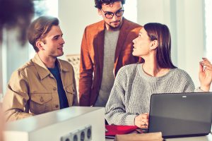 Drei junge Menschen diskutieren miteinander in einem B&uuml;ro