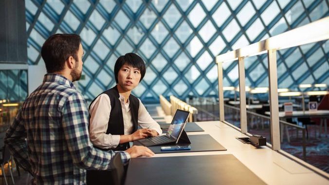 Woman and man sitting at a desk having a conversation in the Seattle Public Library with Surface Pro 4
