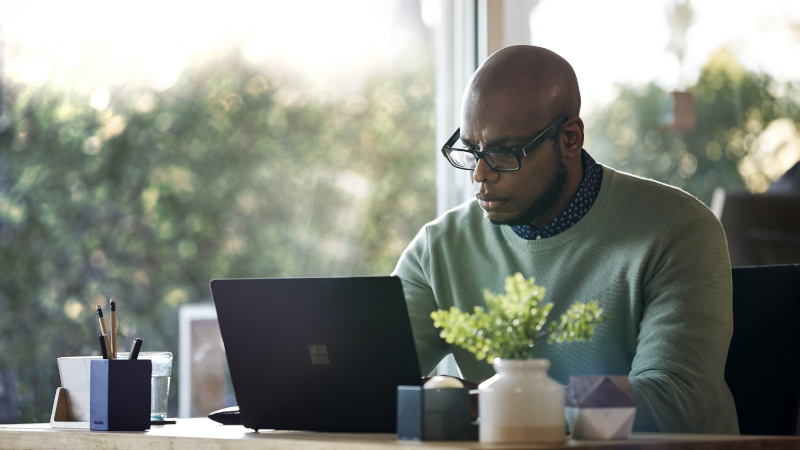 Ein Mann arbeitet zu Hause auf dem Surface Laptop 2