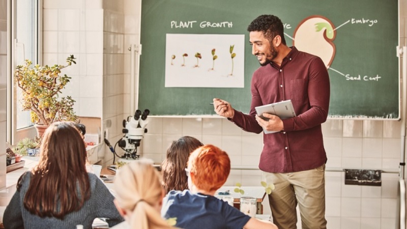 Ein Lehrer steht vor der Tafel und unterrichtet Sch&uuml;ler