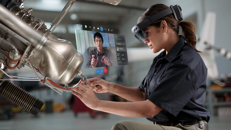 Eine Arbeitnehmerin arbeitet in einer Fabrik mit einem entfernten Assist-Hologramm