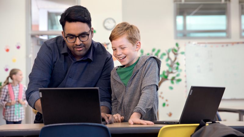 Mann hilft m&auml;nnlichem Studenten auf einem Laptop