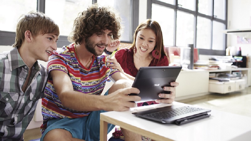 drei Studenten, zwei M&auml;nner und eine Frau, sitzen an einem Tisch und schauen gemeinsam auf ein Tablet PC