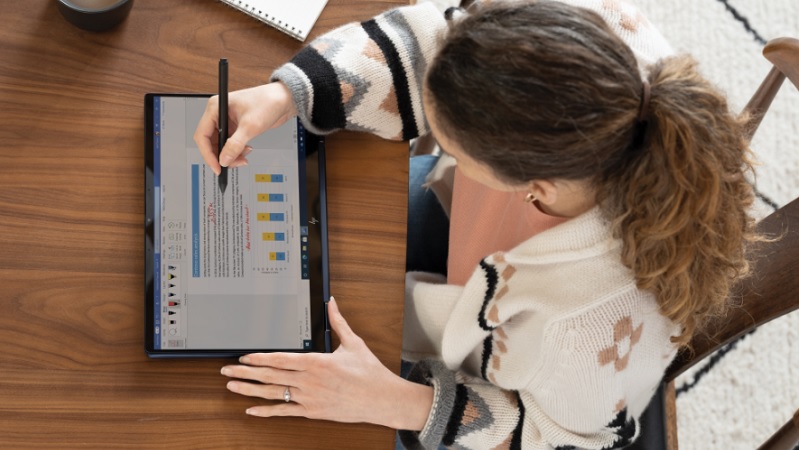 &Uuml;berkopf-Ansicht einer Frau, die von zu Hause aus an ihrem Esstisch auf einem HP Elite Dragonfly im Tablet-Modus arbeitet und eine Microsoft Word-Datei anzeigt