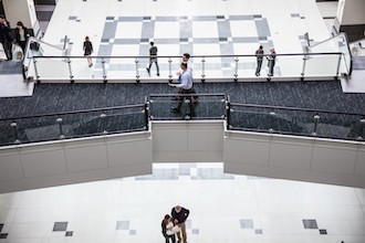 Image of two men walking and talking with each other in a corporate building