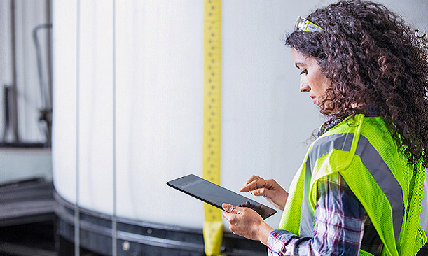 A field service worker in a yellow reflective vest working on a Microsoft tablet
