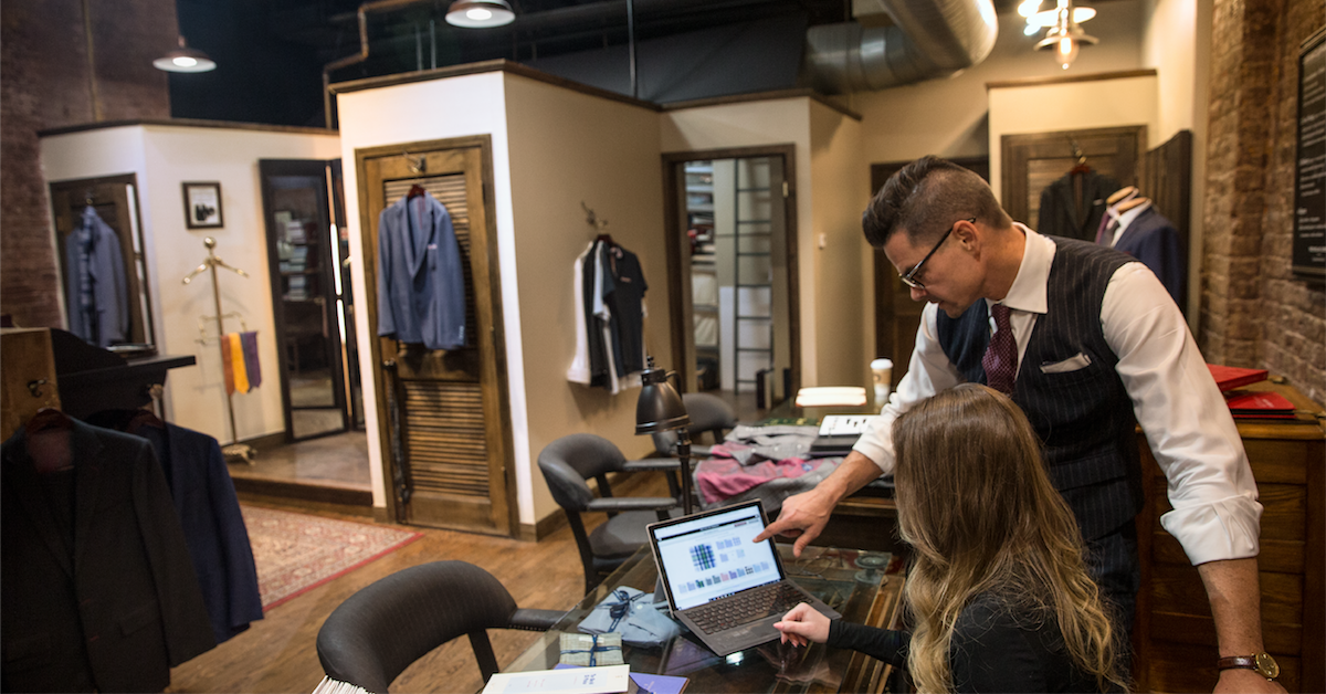 Two retail employees working from a Microsoft laptop in a high-end clothing store