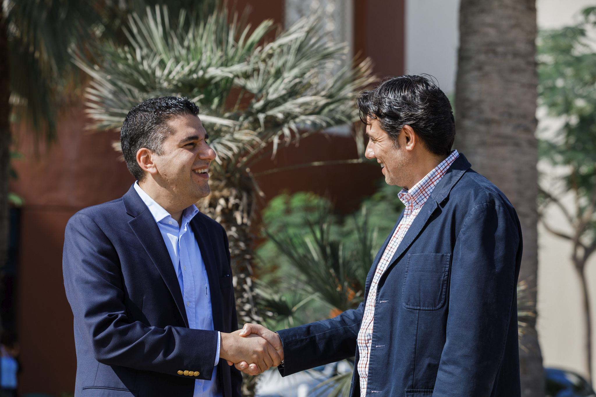Two men in suits standing outside shaking hands