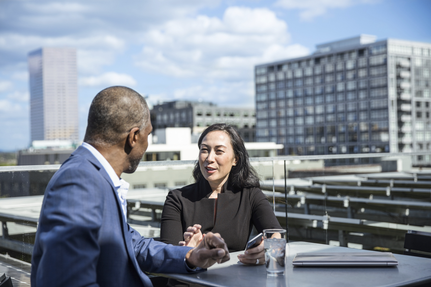Two business people meeting outside with a city skyline behind them