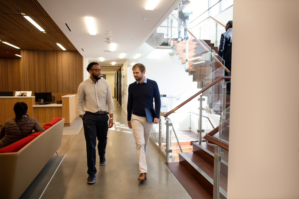 Two people walking down a bright hallway