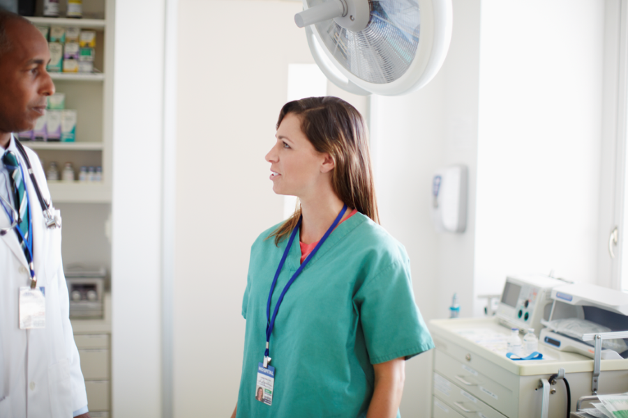 Two healthcare employees talking in a hospital room