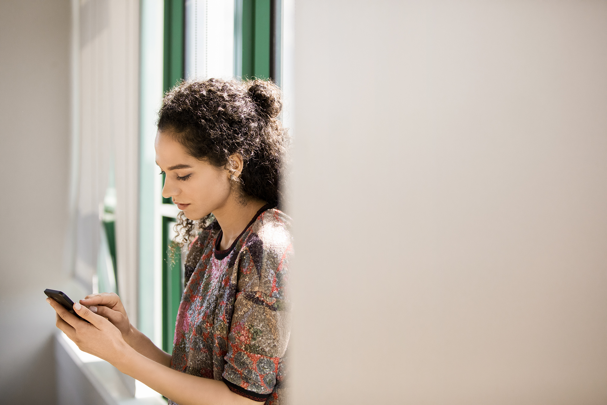 Young, small business female with phone in modern workplace