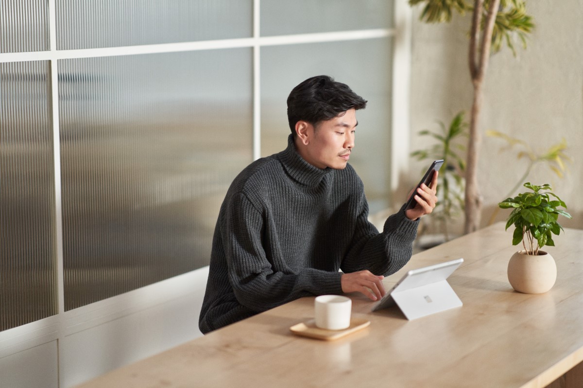 Customer using secure multi-factor authentication on a mobile phone and a tablet while working remote from a café