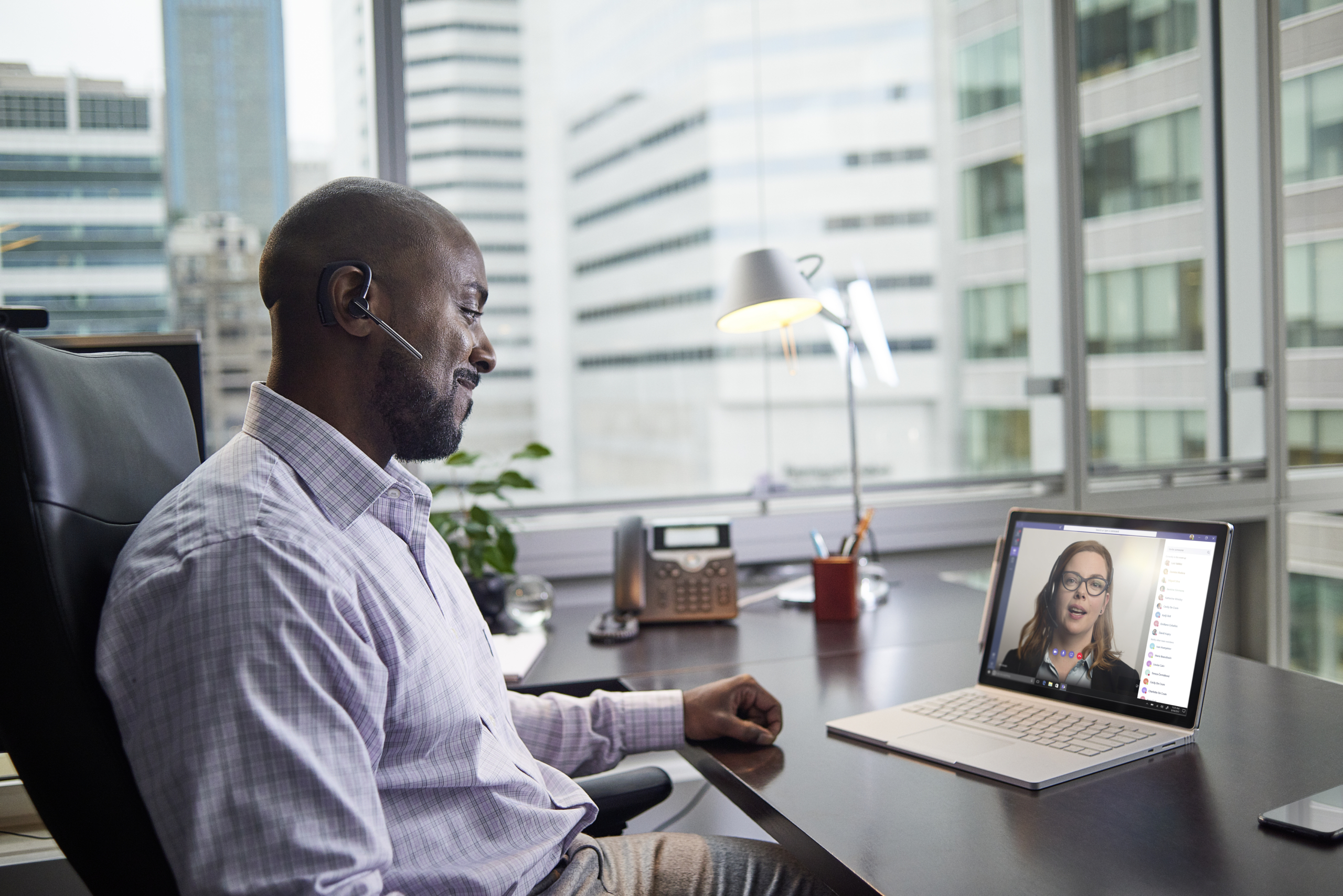 Male business executive working on a Surface Pro Book at desk, running Microsoft Teams