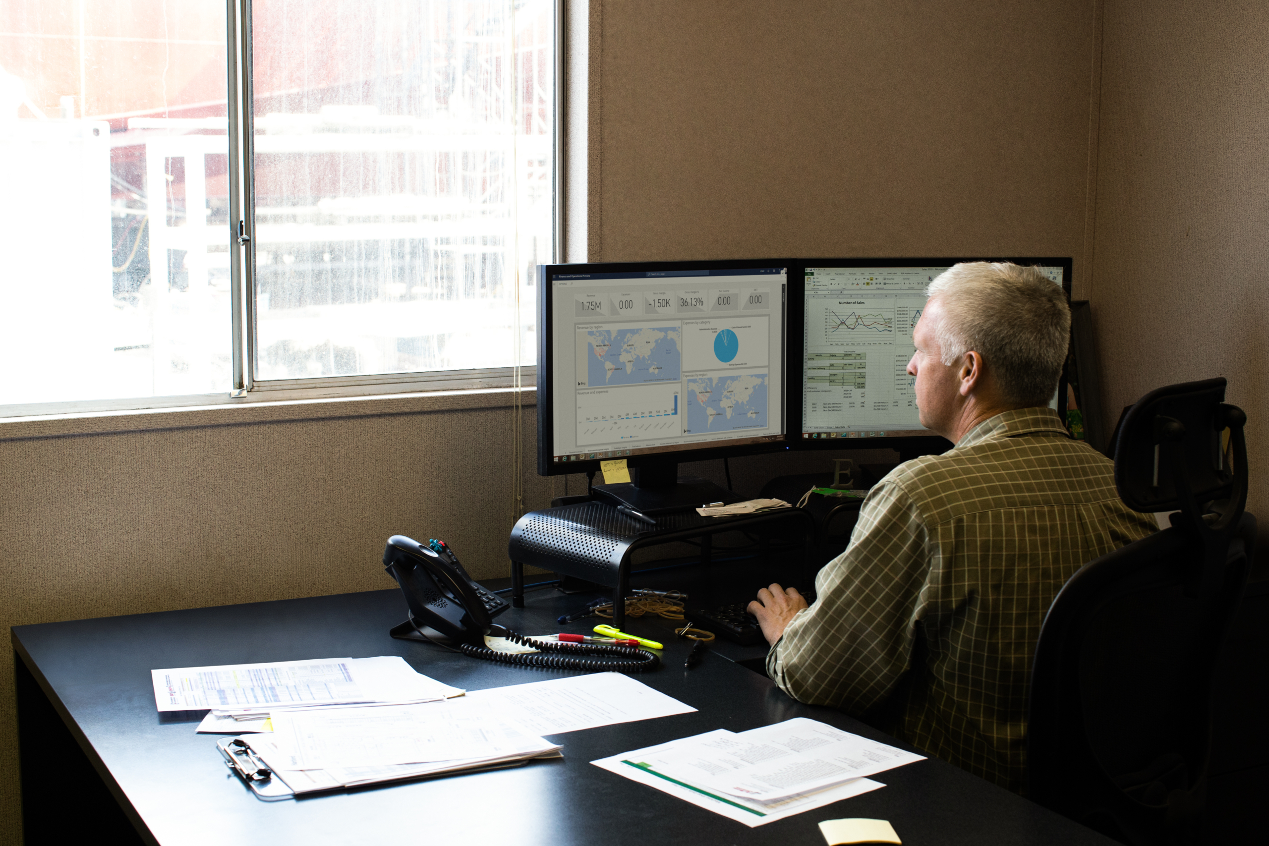 Operations manager at work in his office; shipyard is outside his window