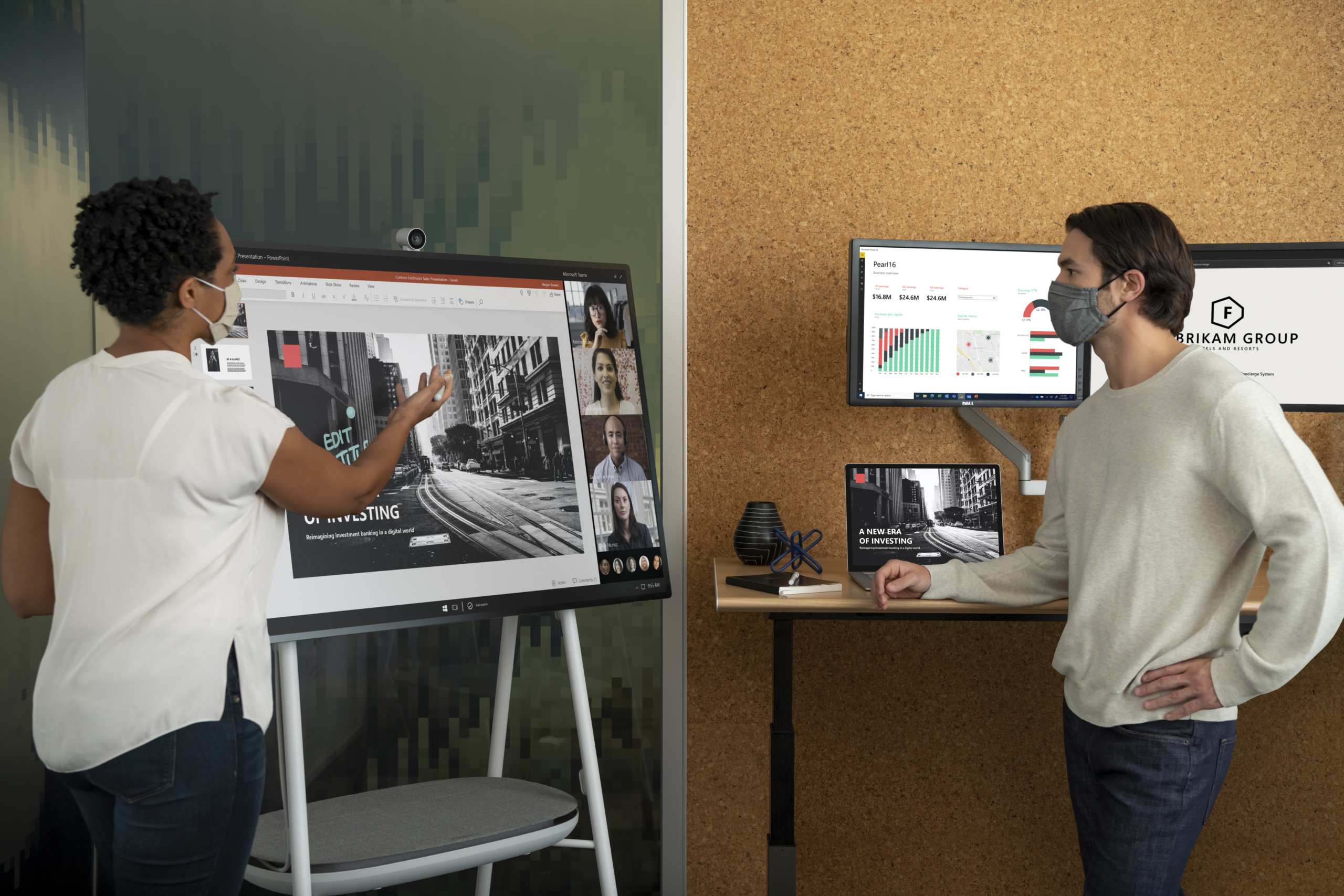 Two adults in masks collaborating on a PowerPoint presentation in an office while using a Microsoft Surface Hub 2S 50&rdquo; device during a Teams video call