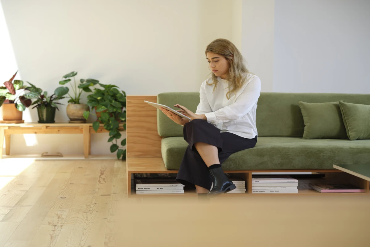 A female architect sitting on a green couch using a Surface tablet