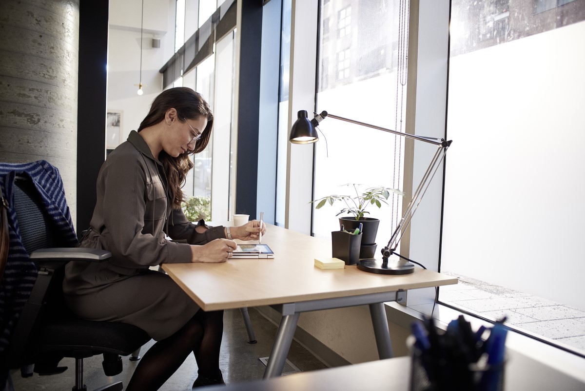 Female small business professional at desk working on an HP Elite Book using Microsoft Word; open office; stylus