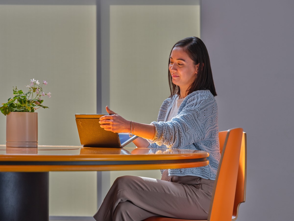 Business person closing Lenovo ThinkPad X1 Fold while sitting at a conference room table