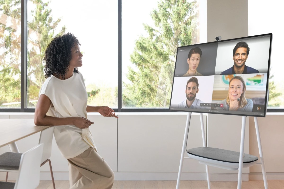 A person in an office along engaging with a Microsoft Teams calls with four faces on video