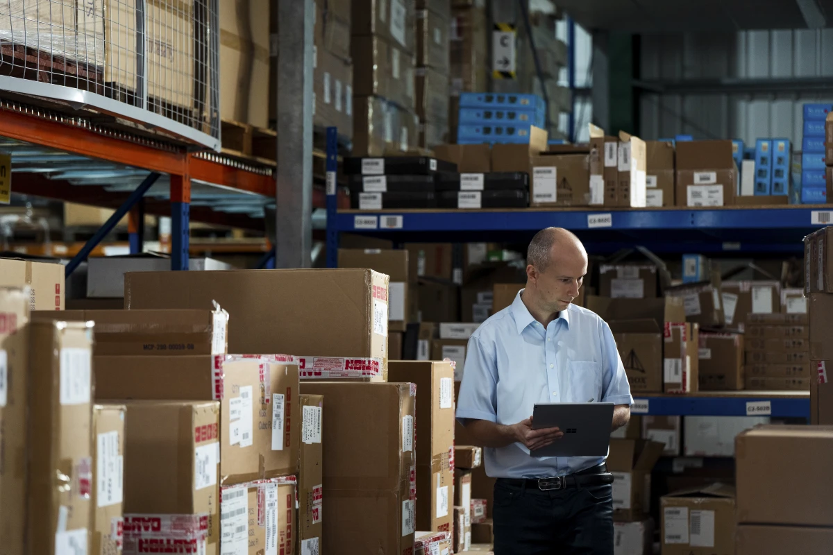A Firstline Worker in a warehouse using a Surface device as a tablet to make notes