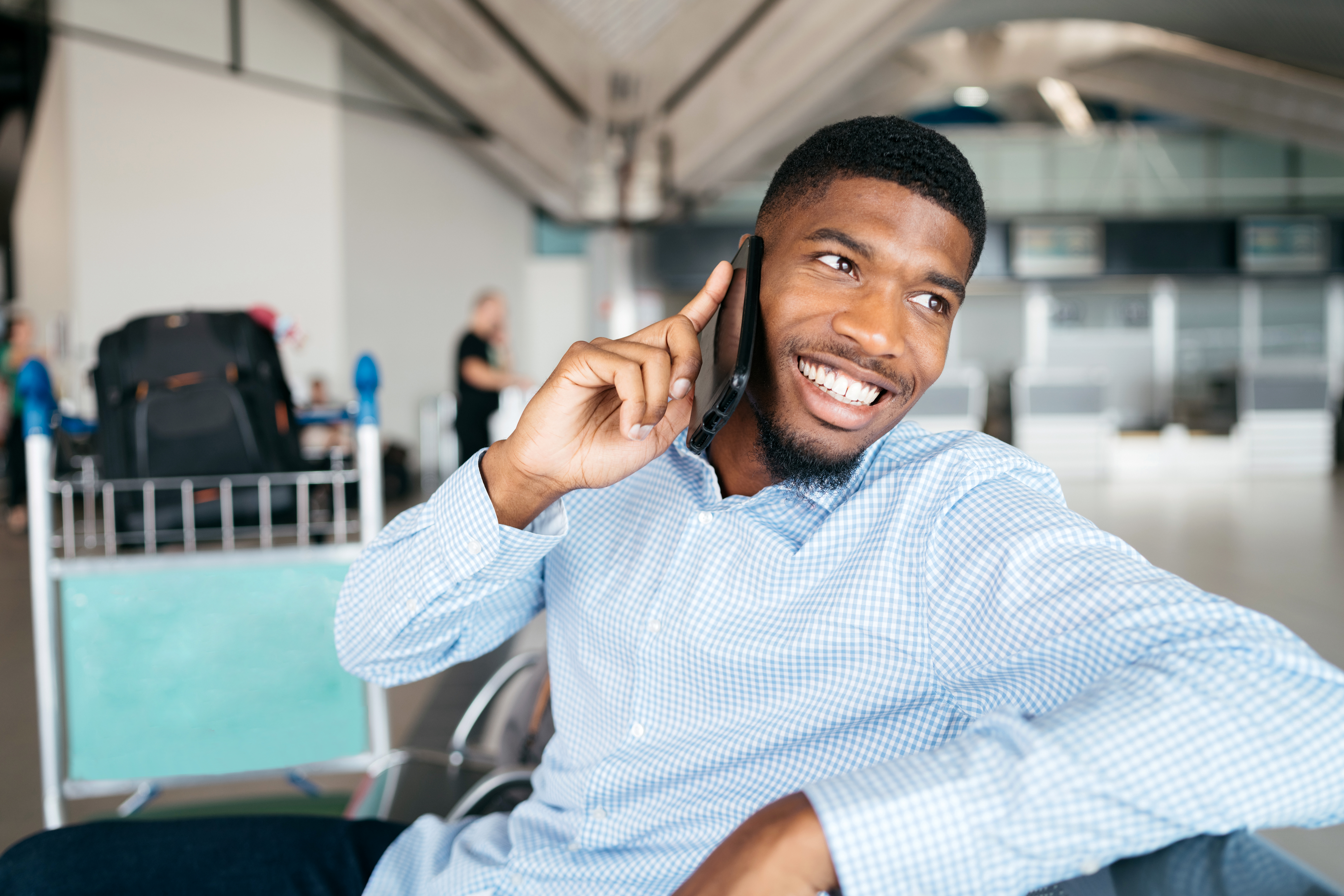 Photo of a smiling young man on the phone at the airport
