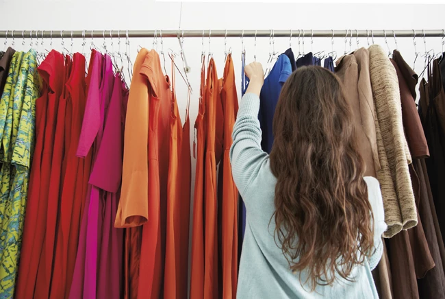 Photo of a woman browsing a rack of clothing in a retail store