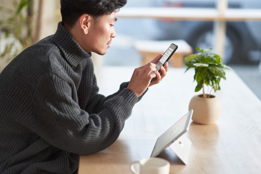 Man sitting at a table, looking at a mobile phone in his hand