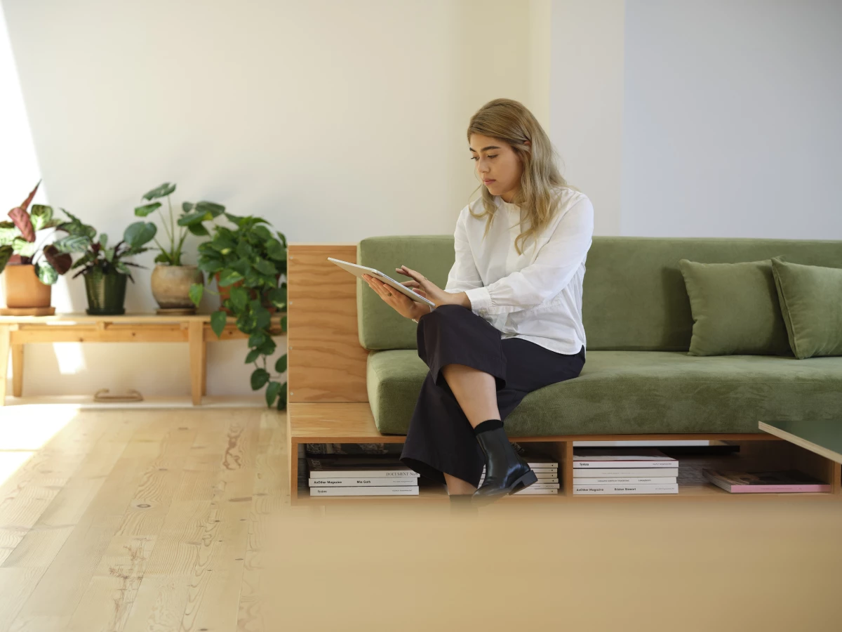 A woman sitting on a couch, working on a tablet
