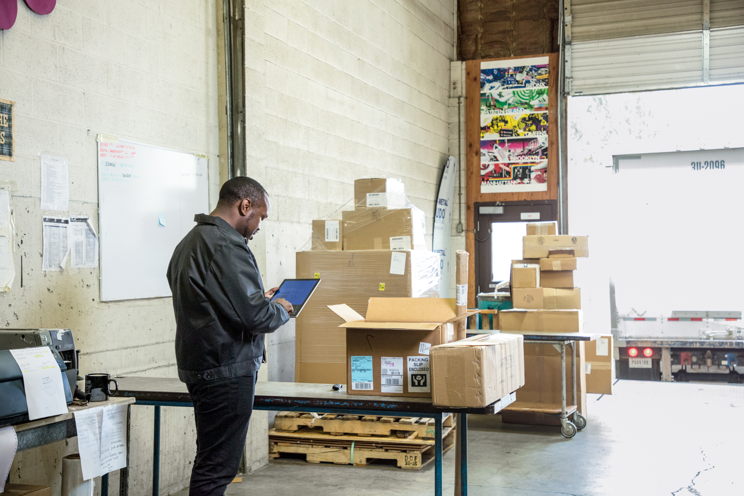 Male warehouse worker at loading dock using Dynamics 365 app on tablet