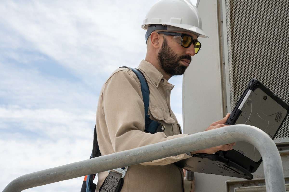 Field engineer viewing data on a laptop after inspecting turbines on a wind farm