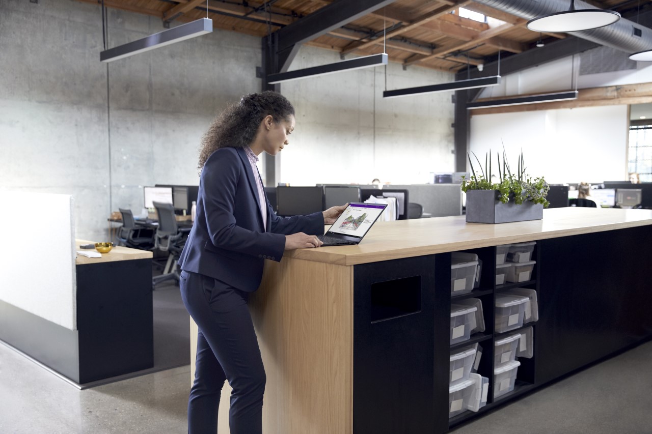 Backed out photo of CEO in SMB architectural design firm reviewing sketches and comments made in OneNote by her team in between meetings