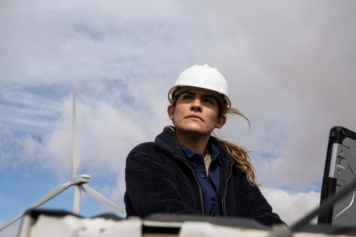 Field engineer using a laptop on truck tailgate to review data after inspection of turbines on a wind farm