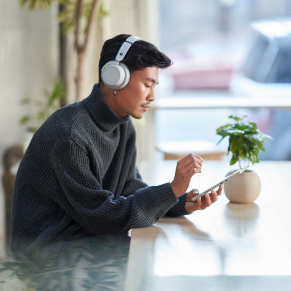 Customer using a tablet while wearing headphones and working securely remote from a caf&eacute;