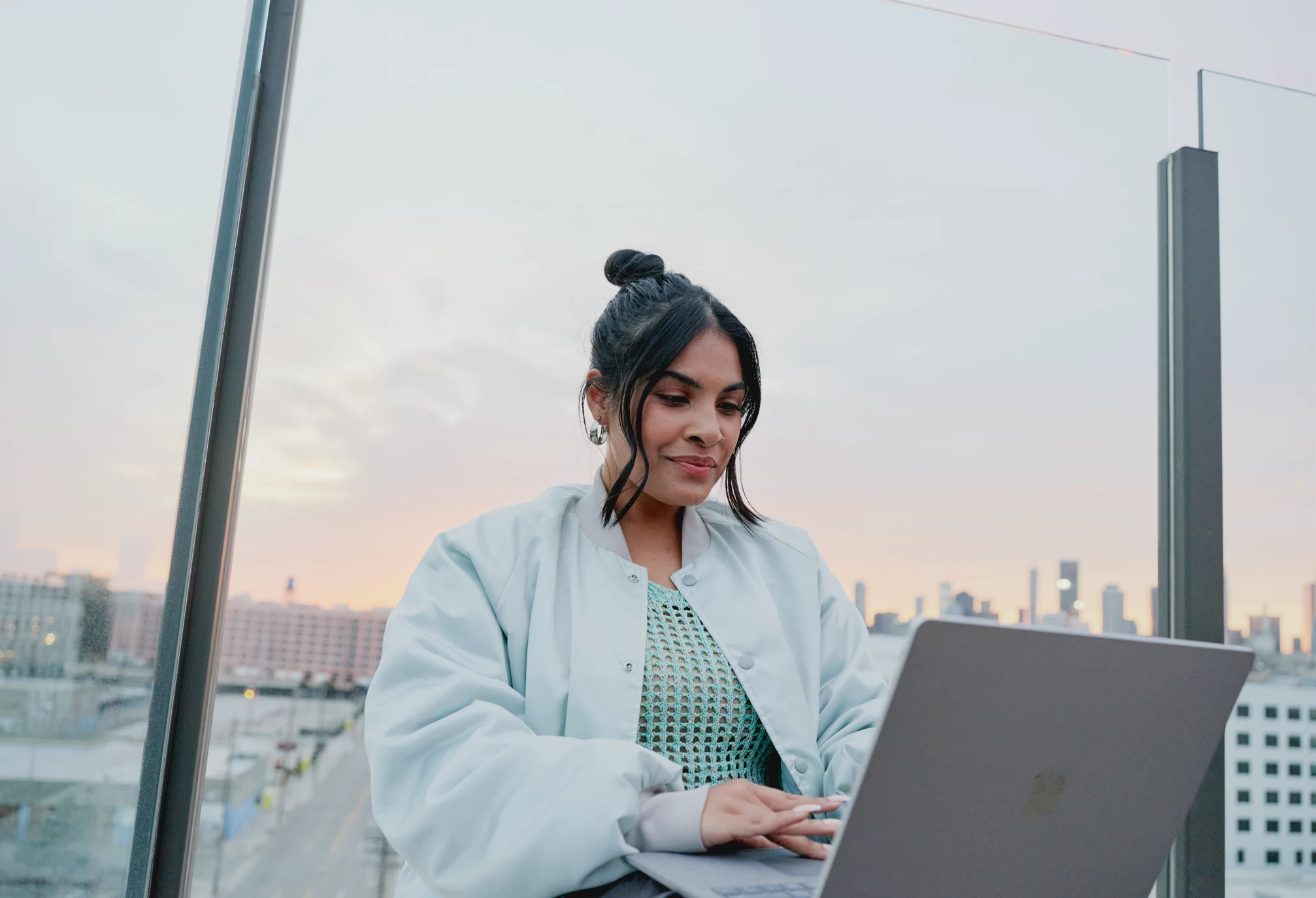 Microsoft 365 lifestyle photography of a female adult sitting outside typing on a Surface Laptop 5