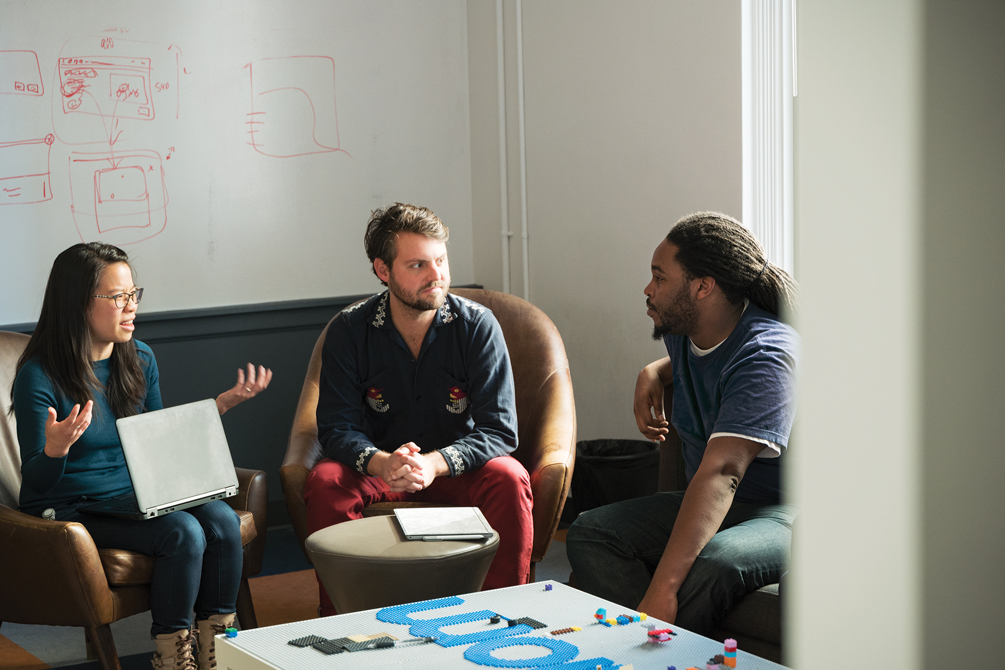 Photo of three colleagues sitting around a table discussing a data maintenance strategy for their organization