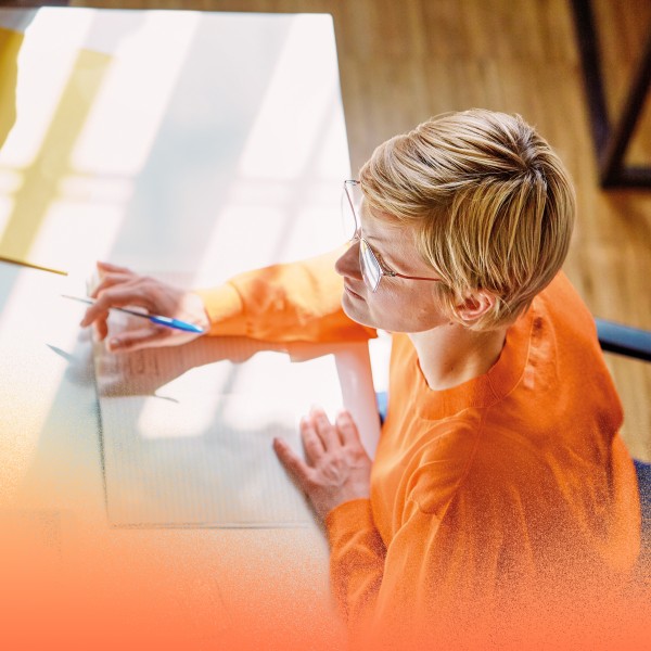 Overhead view of an adult businesswoman with notebook sitting at a desk in an office