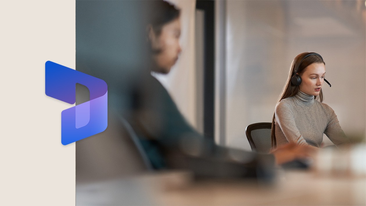 Two coworkers sitting next to each other at a conference room table. There is a thick beige border on the left side of the image, with the Dynamics 365 logo overlaid