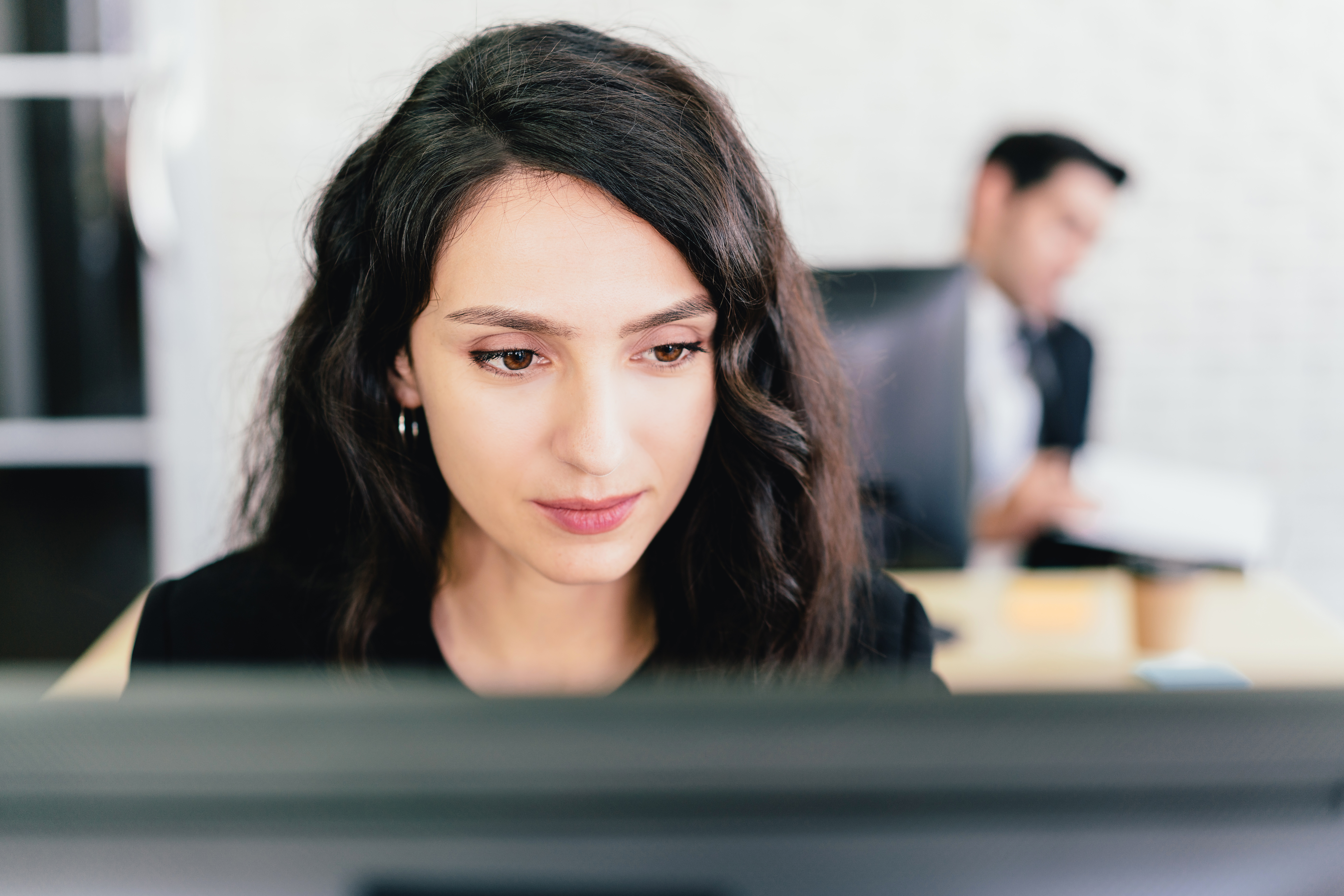Close-up portrait of a Caucasian businesswoman typing and looking on a computer screen with intention at her desk. Concern and fix problems in a corporate office