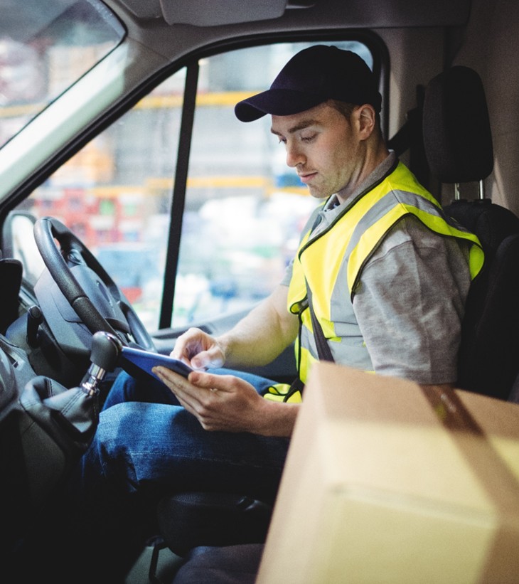 supply chain worker sitting in a truck working on a tablet