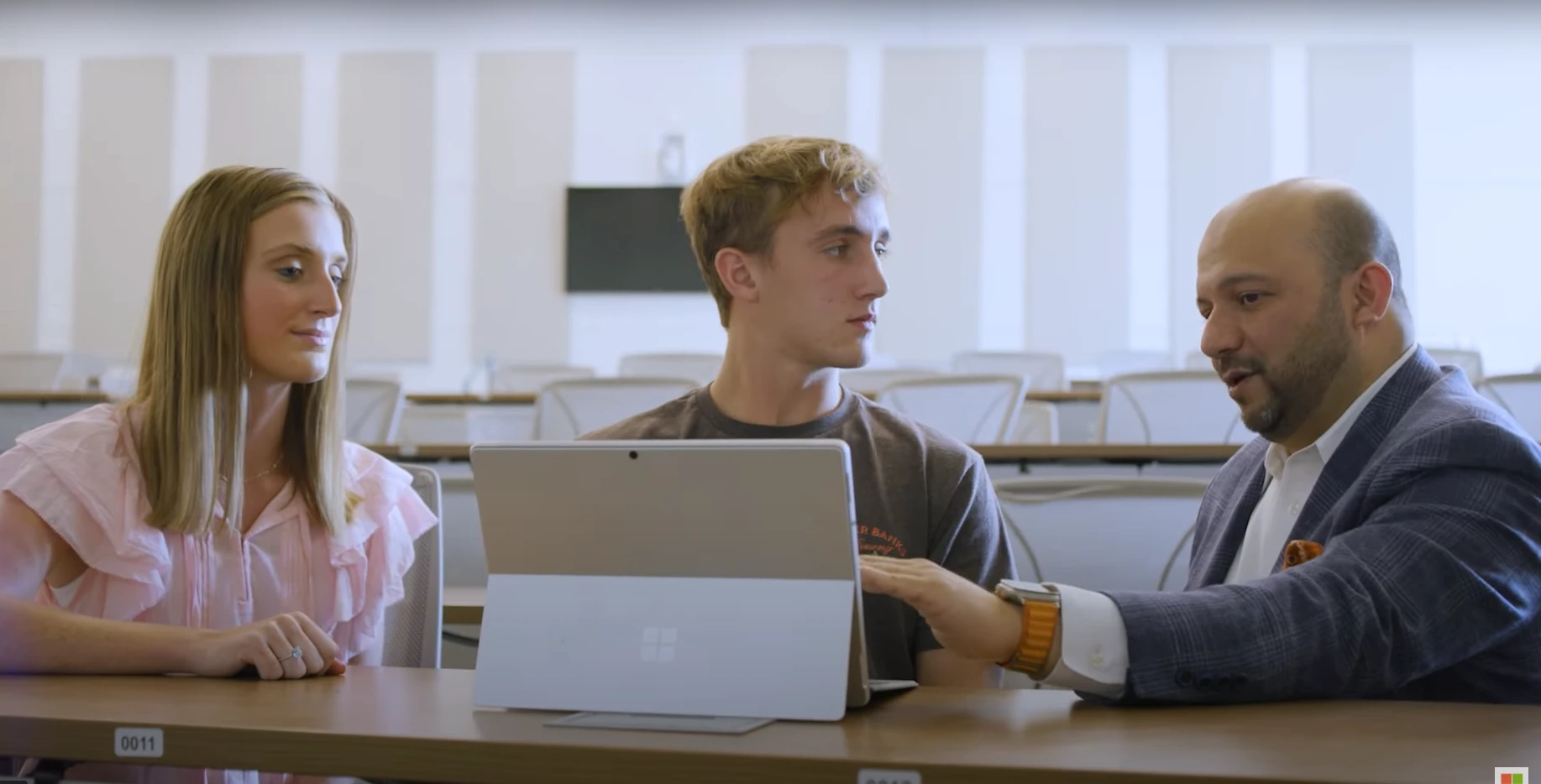 Two students and an educator collaborating in a university classroom