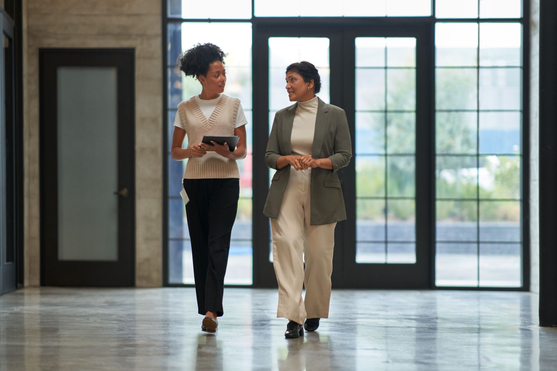 Two education leaders talking together while walking down a school hallway