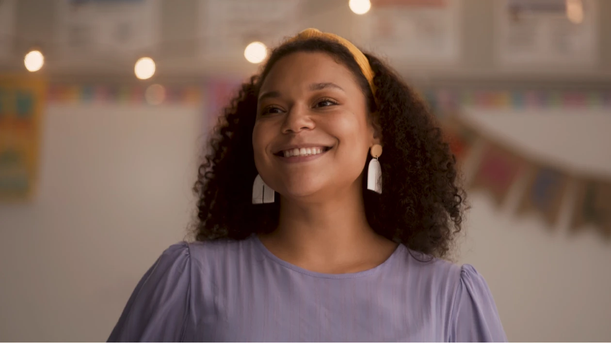 A female teacher smiling while looking at her classroom