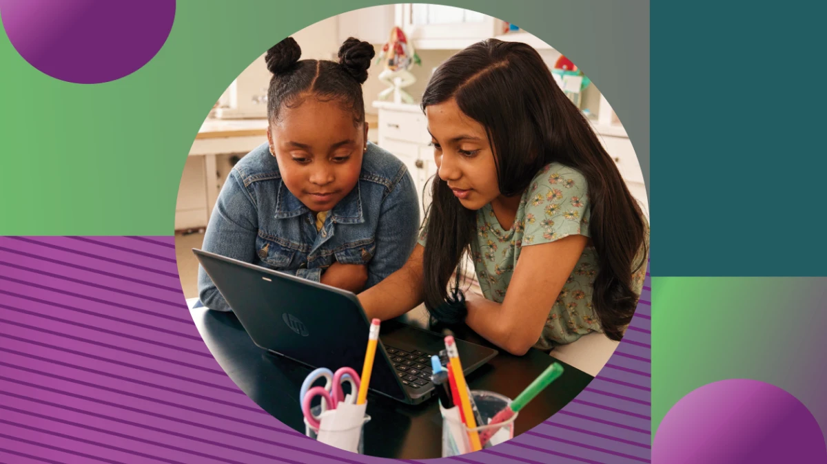 Two students working together on a laptop in a school classroom