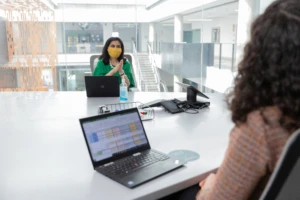 Two business people in a data strategy meeting. They are wearing facemasks,