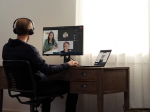 A man sitting at a desk on a Teams meeting. Virtual meetings can drive sustainability goals.
