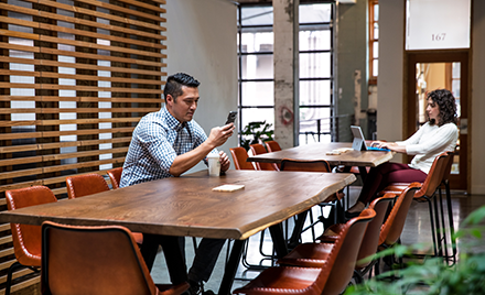 Image of two workers working at separate tables in a casual office environment