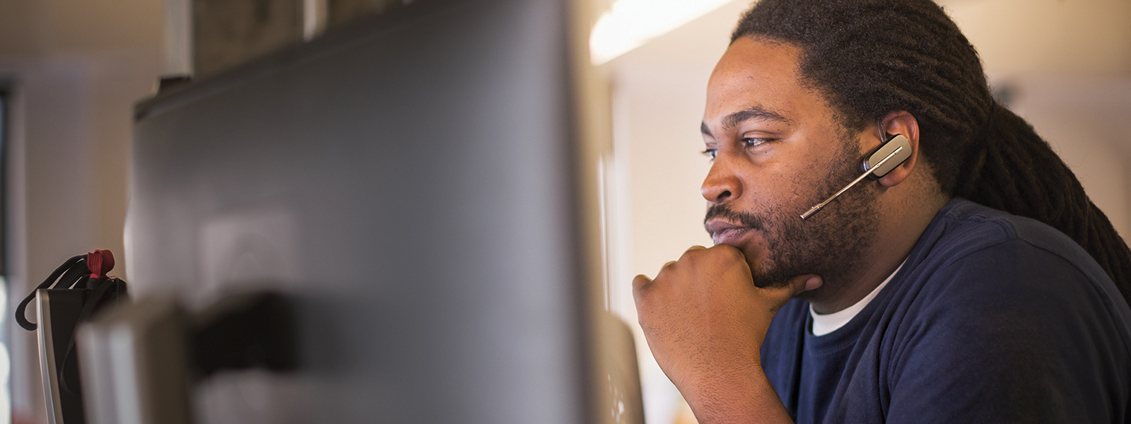 Image of a firstline worker looking at several computer monitors