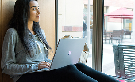 Image of a worker smiling out a window with her laptop open