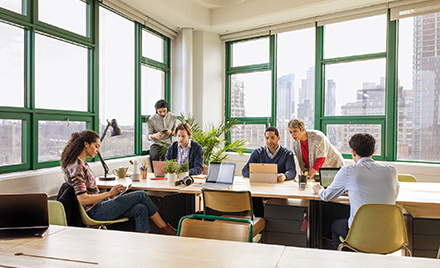 Image of a group of coworkers collaborating in a conference room, each on a variety of different devices